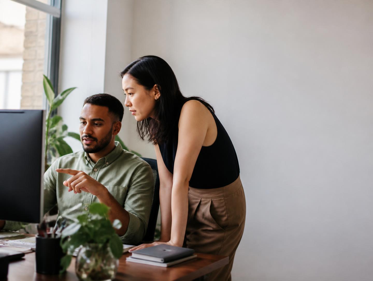 Two colleagues reviewing incoming customer enquiries at a shared screen